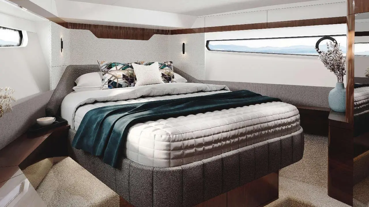 Stylish bedroom with a large bed, decorative pillows, and a vase, featuring a window overlooking a scenic view.